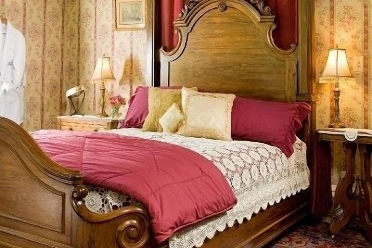 A four-poster bed with a canopy, a wooden headboard, and a floral-patterned bedspread.