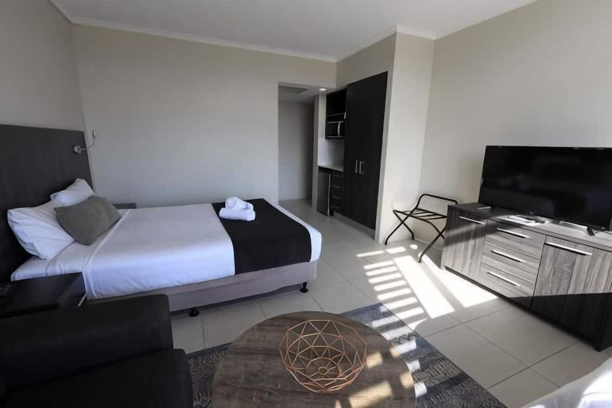 Una habitación de hotel moderna con cama, televisión, escritorio y armario.