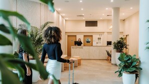 A reception area with a reception desk, a waiting area with chairs, and potted plants. - Alivio Hotel Cairns (Cairns)