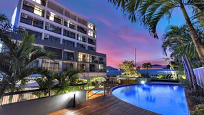 A multi-story hotel with a swimming pool, palm trees, and a sunset view. - Alivio Hotel Cairns (Cairns)