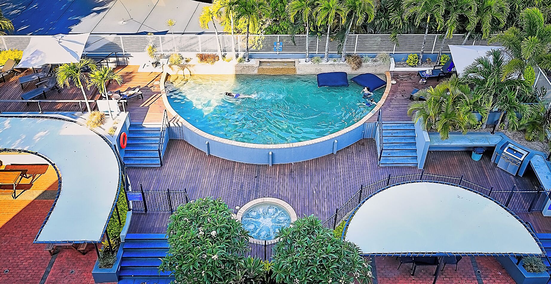 A circular pool with a hot tub, surrounded by wooden deck and lounge chairs.