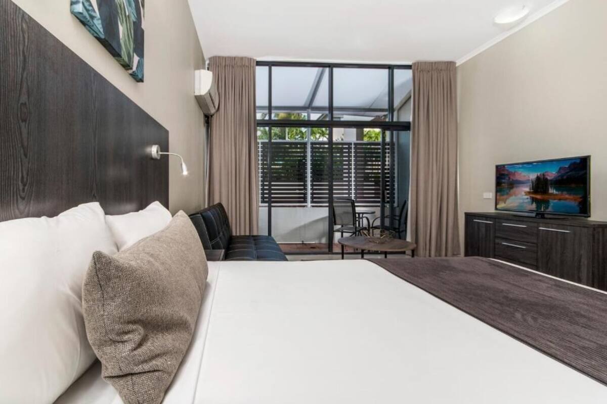 Una habitación de hotel moderna con una cama grande, un escritorio y un televisor.
