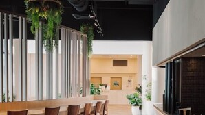 A modern bar area with a long counter and several stools, a reception desk in the background, and a ceiling with exposed ductwork. - Alivio Hotel Cairns (Cairns)