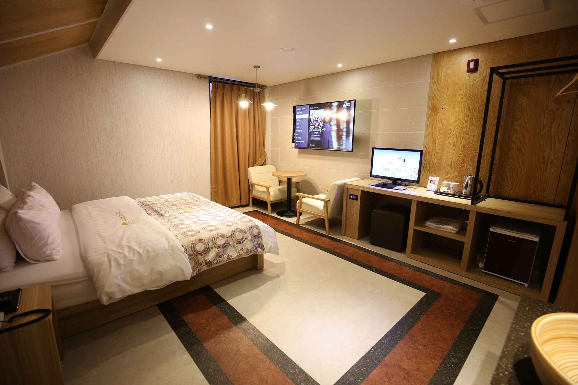 Habitación de hotel con cama, escritorio con computadora, televisor y una pequeña zona de estar.