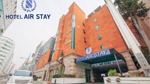A hotel named HOTEL AIR STAY with a modern orange facade and a prominent entrance sign.