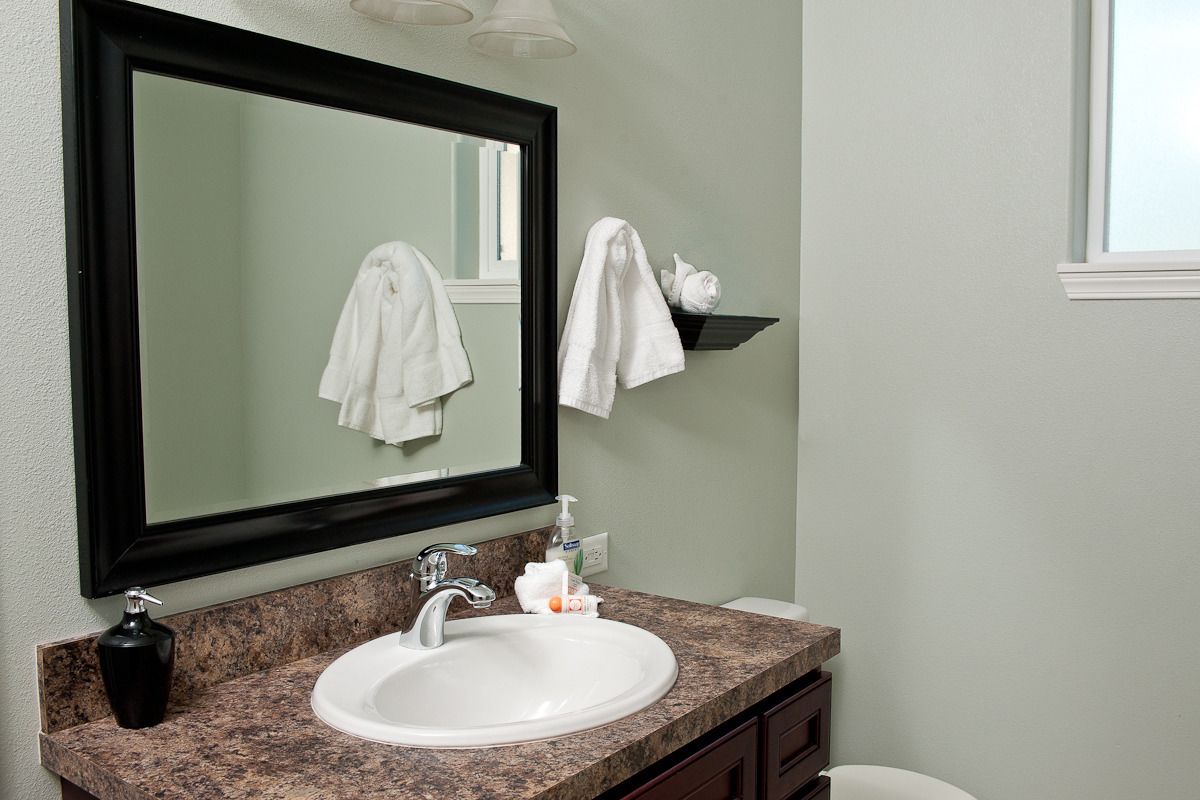 A bathroom with a white sink, a black soap dispenser, a mirror, and a towel rack.