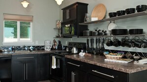 A kitchen with dark cabinets, a granite countertop, and various kitchen appliances. - Keystone Vacation Rentals-Ocean View Condos (Depoe Bay)