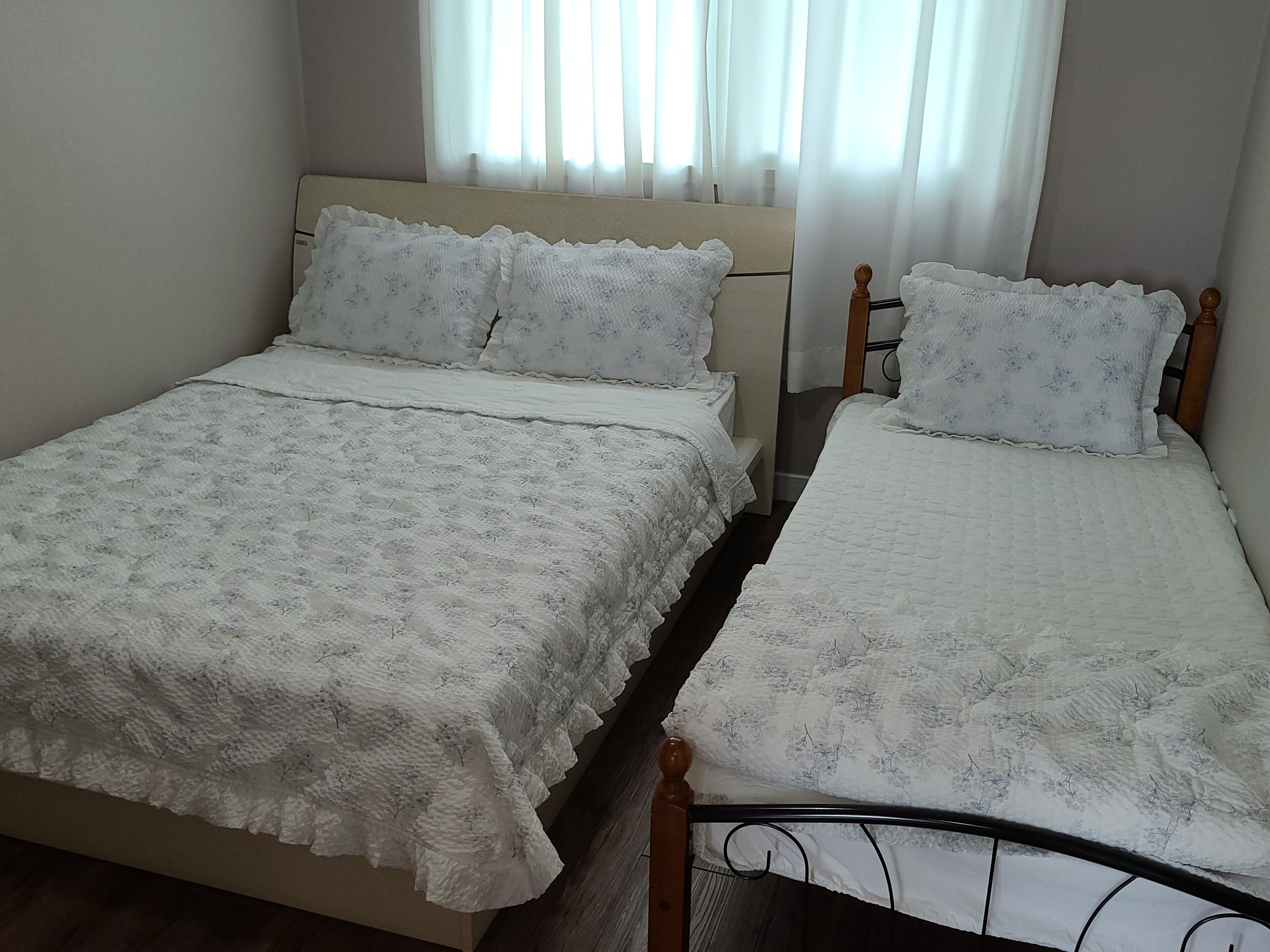 Une chambre à coucher avec deux lits, chacun recouvert d’une couvre-lit à motifs floraux blancs et agrémenté d’oreillers assortis.
