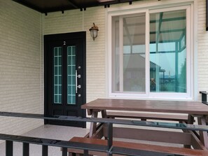 A front porch with a black door marked with the number 2, a large window, and a wooden bench. - Santa Fe Pension (Namhae)