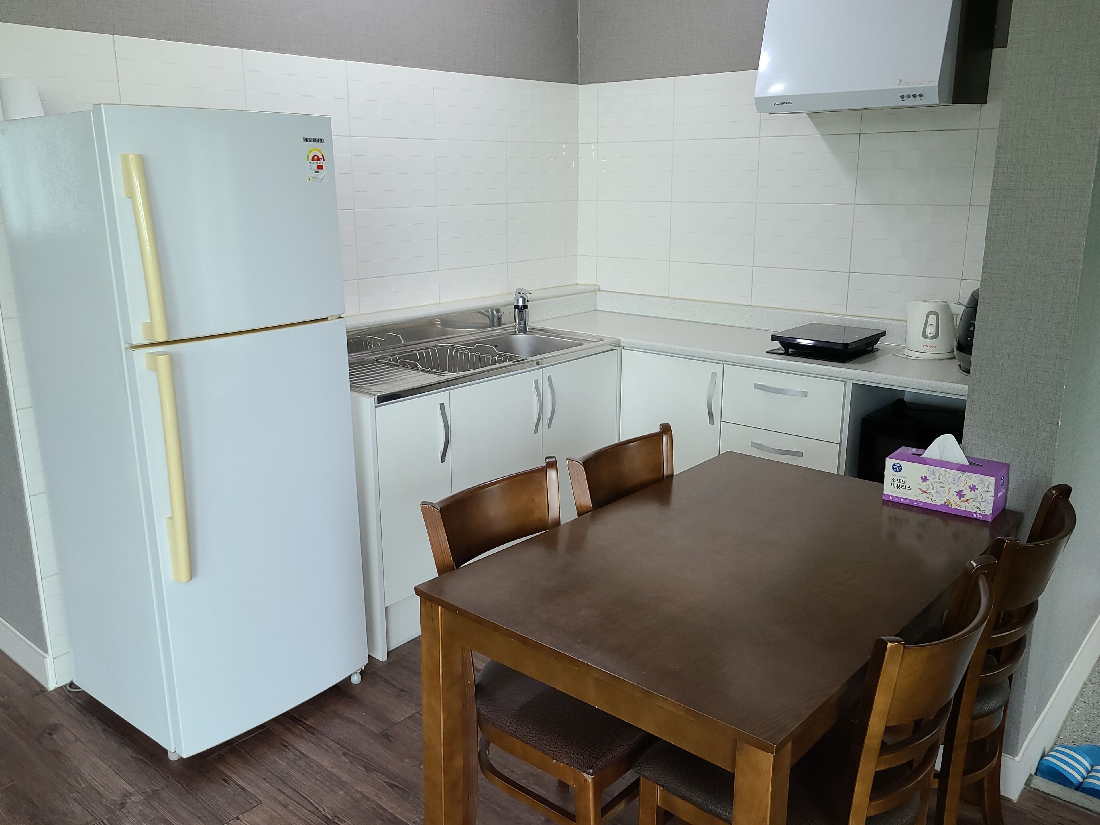 Una cocina compacta con un refrigerador blanco, un lavamanos y una mesa de comedor con sillas.