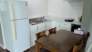 Una cocina compacta con un refrigerador blanco, un lavamanos y una mesa de comedor con sillas.