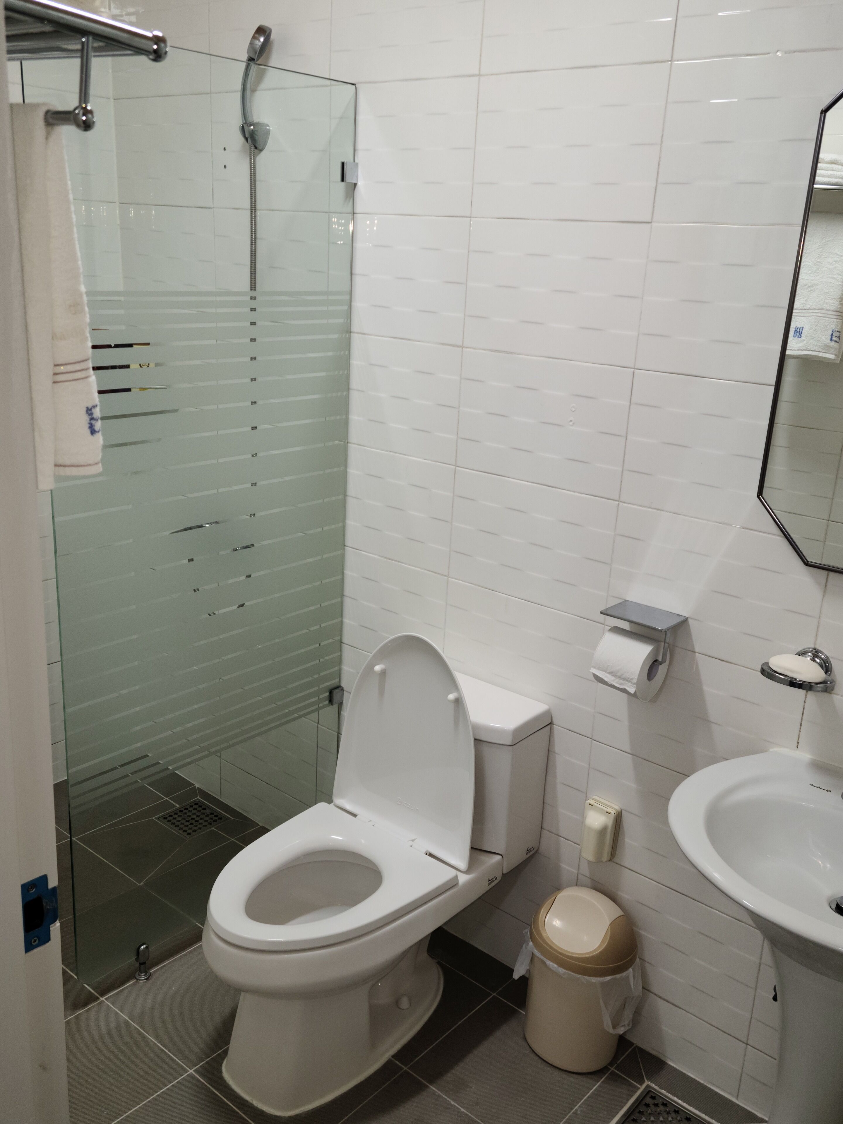 Un baño con inodoro, bidé y cabina de ducha de vidrio.