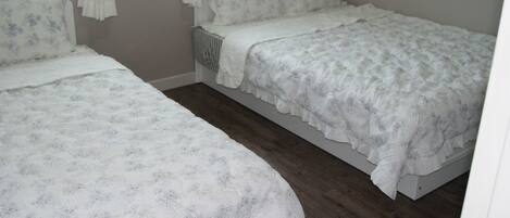 Un dormitorio con dos camas individuales, un radiador y una ventana con cortinas.