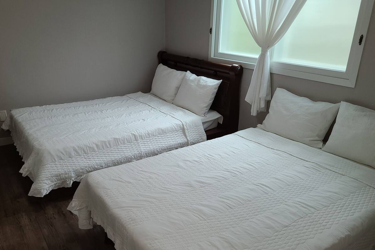 A room with two beds, each with white bedding and a wooden headboard.