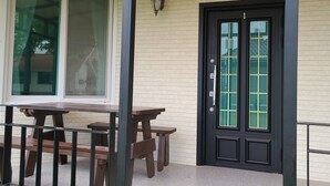 A building exterior with a black door, a window, and a small table with benches.