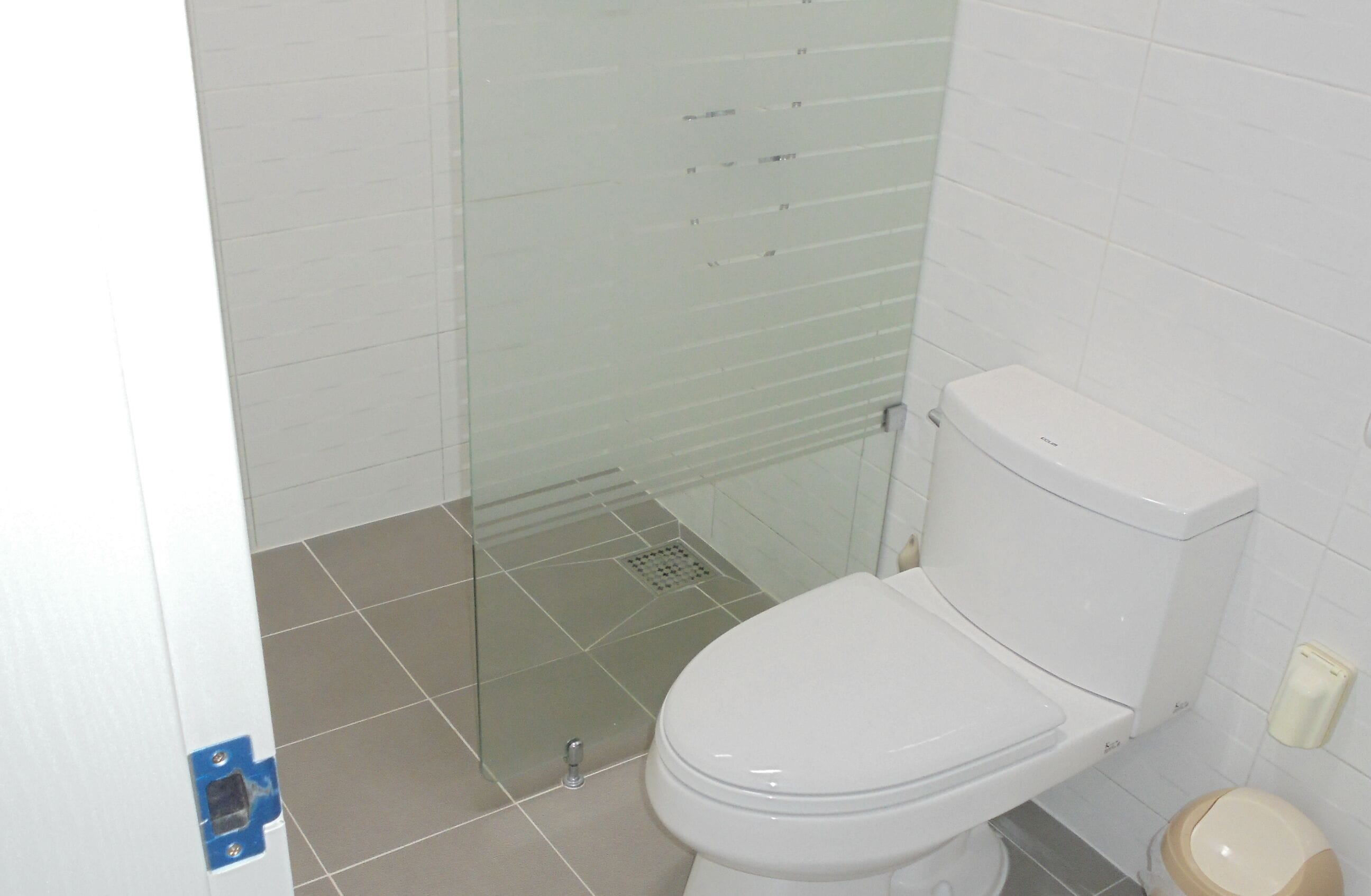 A bathroom with a toilet, a glass shower enclosure, and a tiled floor.