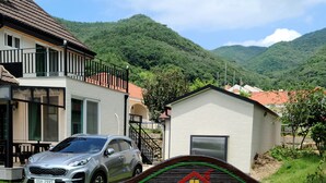 A residential property with a car parked in front, a small house, and a signboard with contact information.