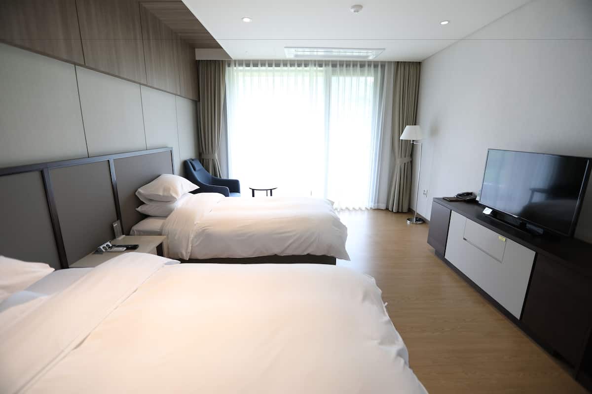 A hotel room with two beds, a TV, and a desk.