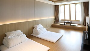 A modern hotel room with two beds, a small table, and a large window with curtains. - Pinehills Hotel (Suncheon)