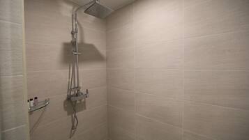 Une douche équipée d’un pommeau de douche à main et d’un robinet fixé au mur.
