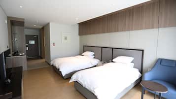 Une chambre d’hôtel avec deux lits, un bureau, une chaise et un téléviseur.