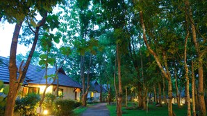 A pathway leading to a row of houses with sloped roofs, surrounded by trees and greenery. - Chiangmai Highlands Golf and Spa Resort (Mae On)