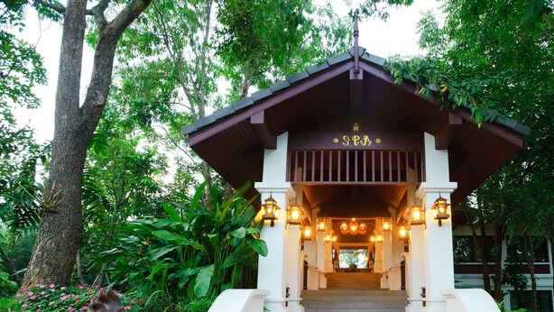 A traditional Thai pavilion with a staircase leading to a covered entrance, surrounded by lush greenery and a statue. - Chiangmai Highlands Golf and Spa Resort (Mae On)