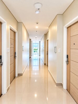 A modern hotel corridor with a long, straight path leading to a bright room with a view. - Hamersons Hotel Cebu (Cebu City)