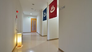 Ein Flur mit einer beleuchteten Stehlampe, einem Rauchmelder und zwei Wimpeln an der Wand.