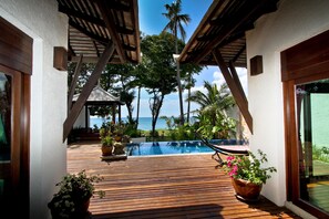 A wooden deck with a pool, surrounded by potted plants and palm trees, leading to a beach view. - Thai Island Dream Estate (Ko Lanta)