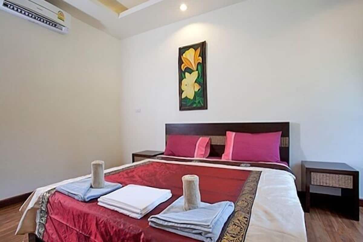 Habitación de hotel con una cama grande, un cuadro en la pared y una mesita de noche con una lámpara.