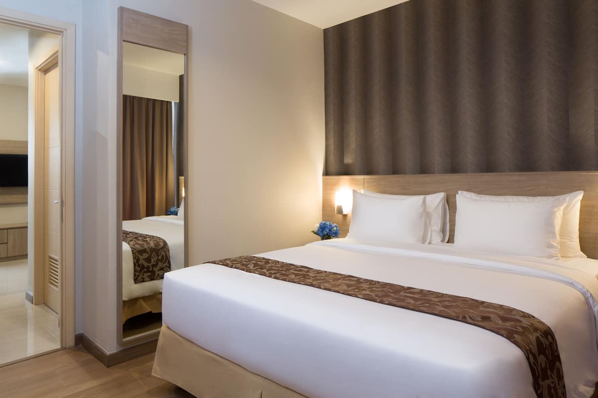 Ein Hotelzimmer mit einem großen Bett, einem Spiegel und einer Wandleuchte.