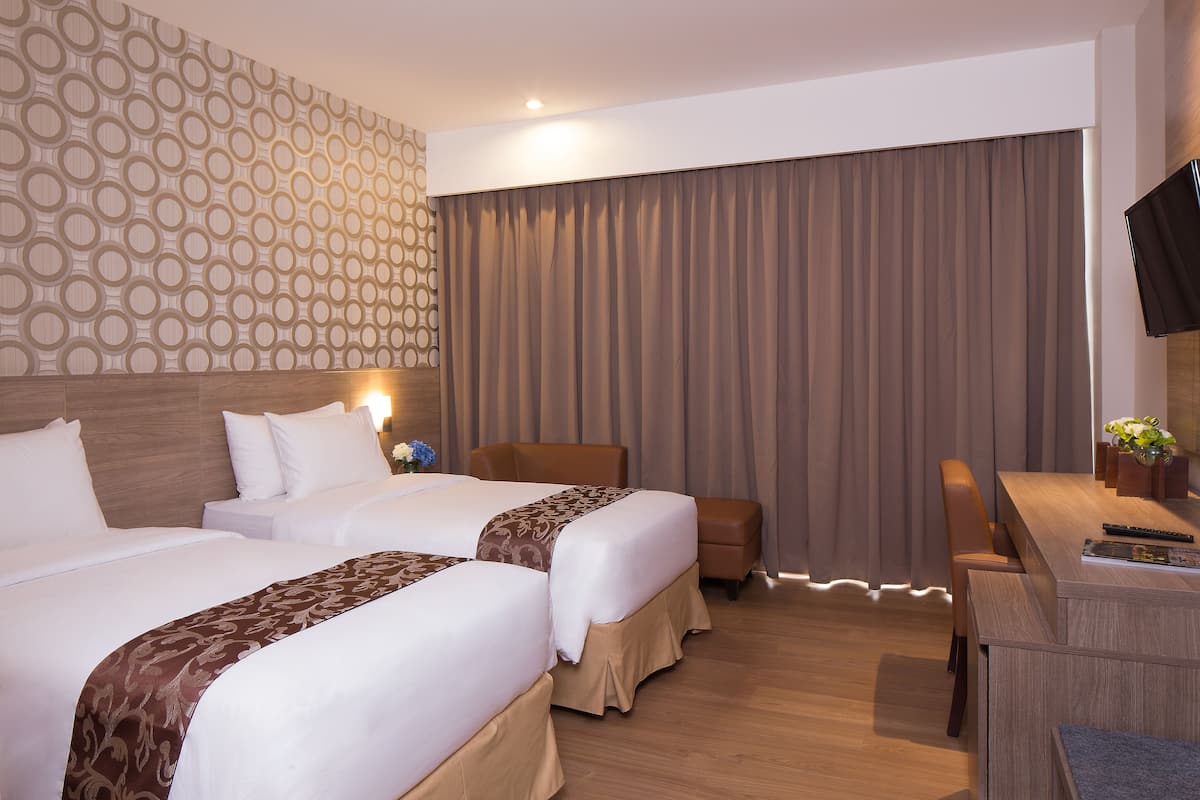 Ein Hotelzimmer mit zwei Betten, einem Schreibtisch, einem Stuhl und einem Fernseher.
