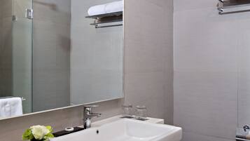 A modern bathroom with a large mirror, white sink, and toilet.