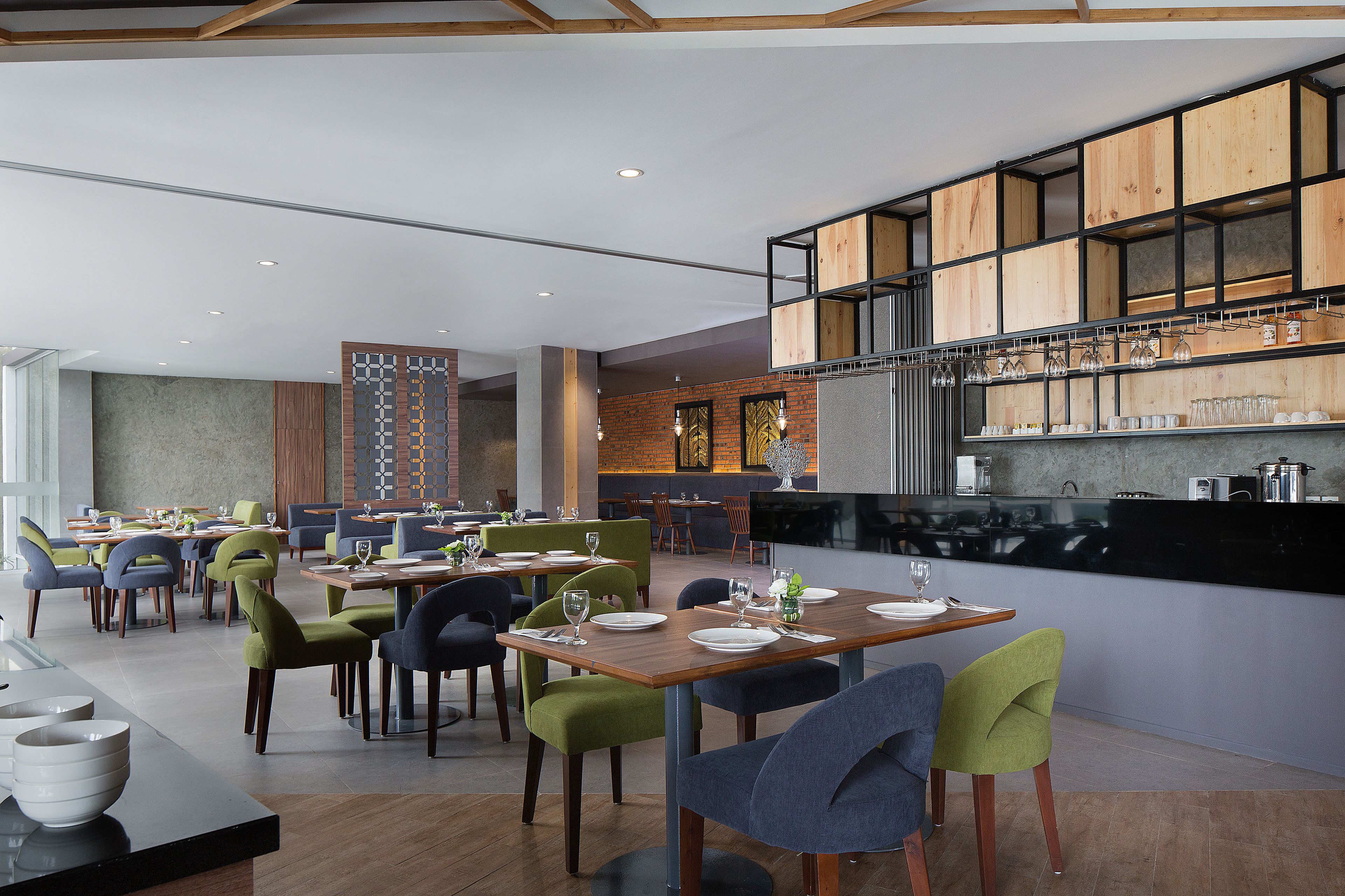 Un restaurant moderne doté de plusieurs tables et chaises, d’un espace cuisine et d’un bar.