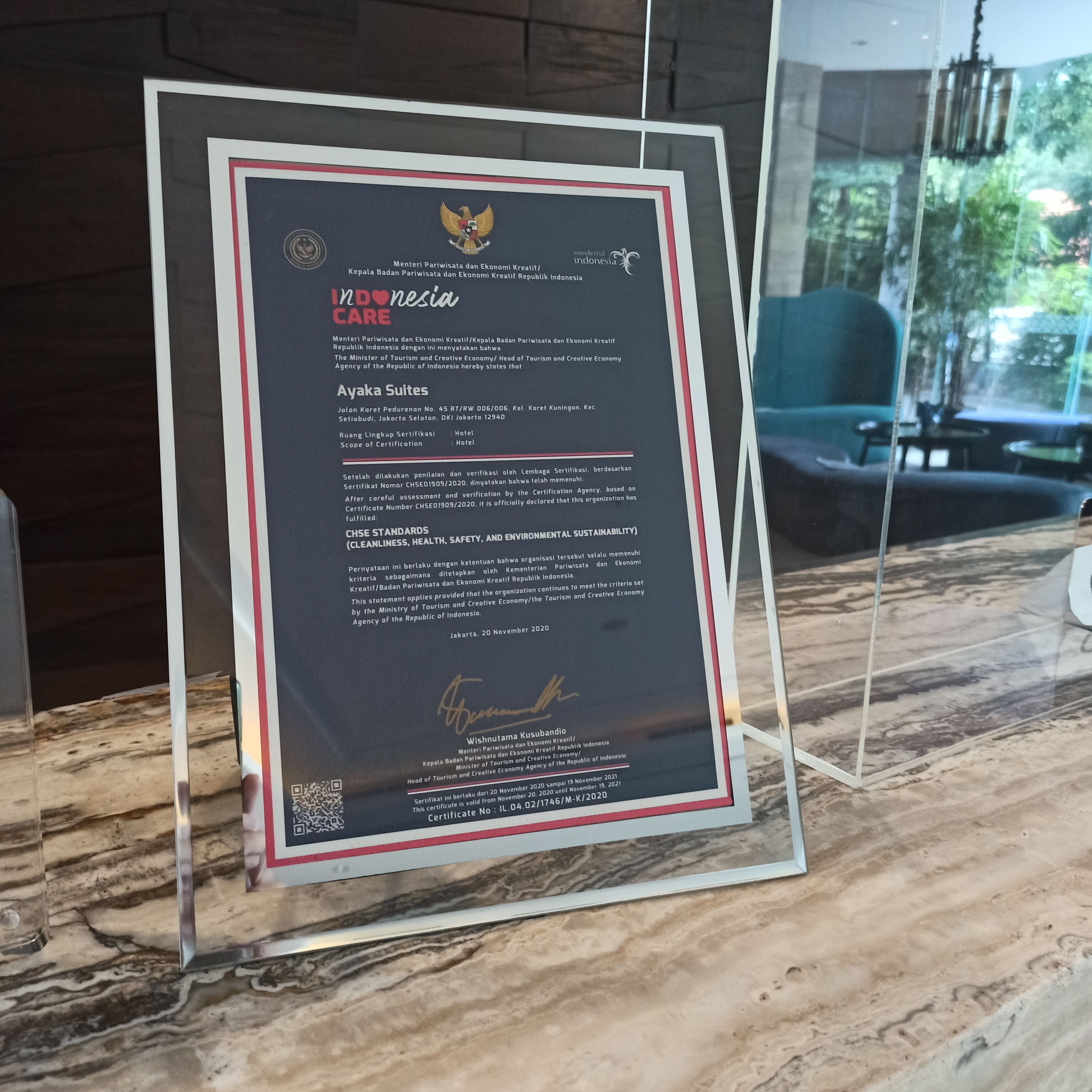 A framed document on a marble surface, detailing Ayaka Suites' certification for cleanliness, health, safety, and environmental sustainability.