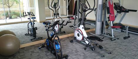 A gym with various exercise equipment including treadmills, stationary bikes, and weight machines.