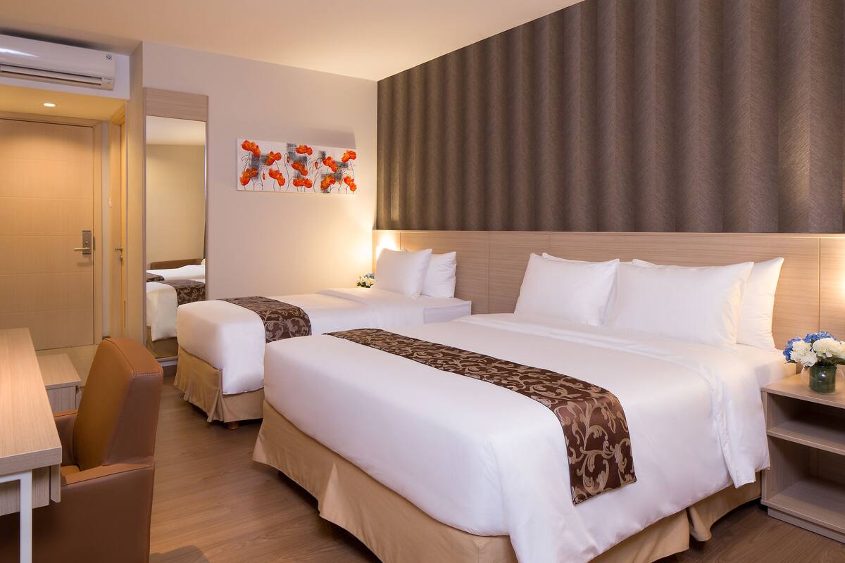Ein Hotelzimmer mit zwei Betten, einem Schreibtisch und einem Stuhl.