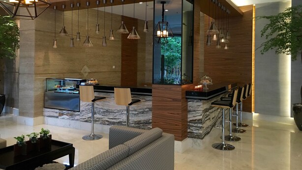 Een moderne lobby met een receptiebalie, een zithoek en uitzicht op het omliggende landschap.