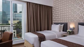 Une chambre d’hôtel avec deux lits, une vue sur le paysage urbain, un balcon et un mur décoré de motifs.