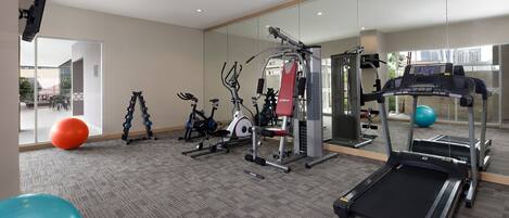 A gym with exercise equipment, a treadmill, and exercise balls.