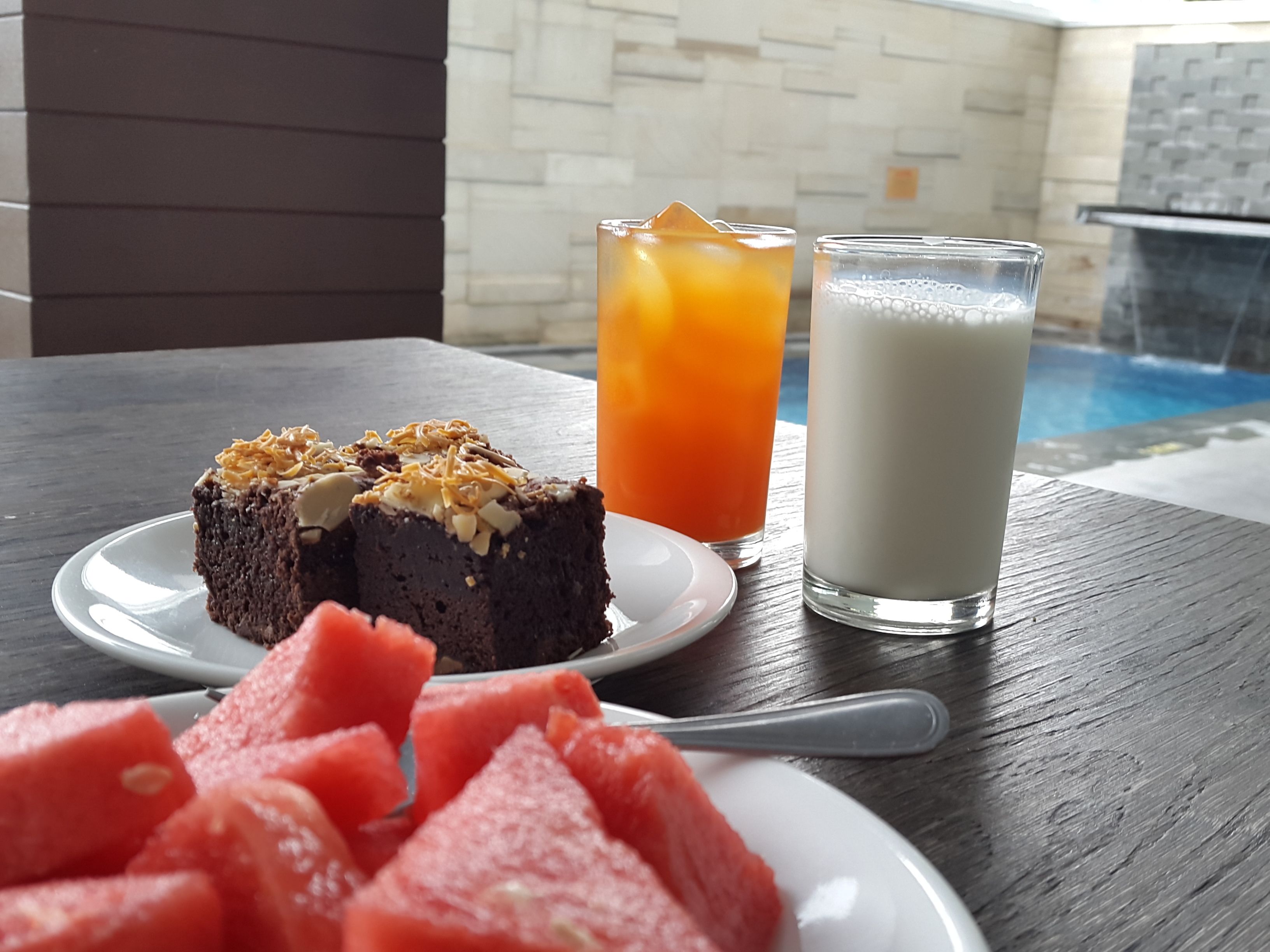 Ein Dessertteller mit Kuchenstück und Wassermelone auf einem Holztisch.