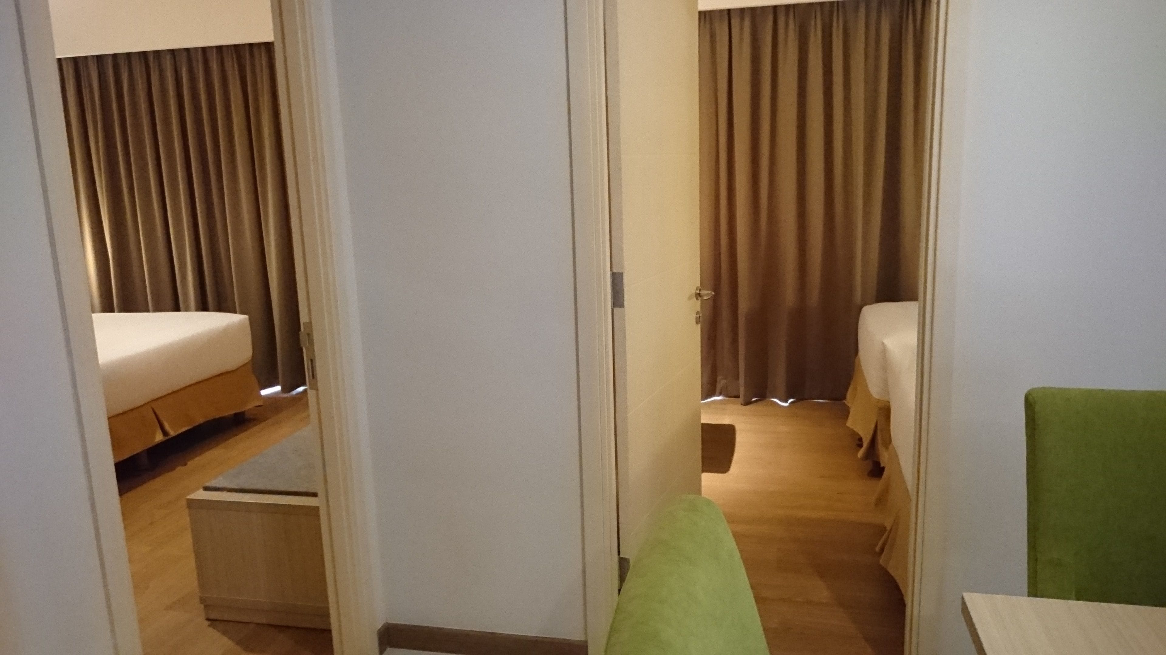 A hotel room with a bed, a green chair, and a wooden cabinet.