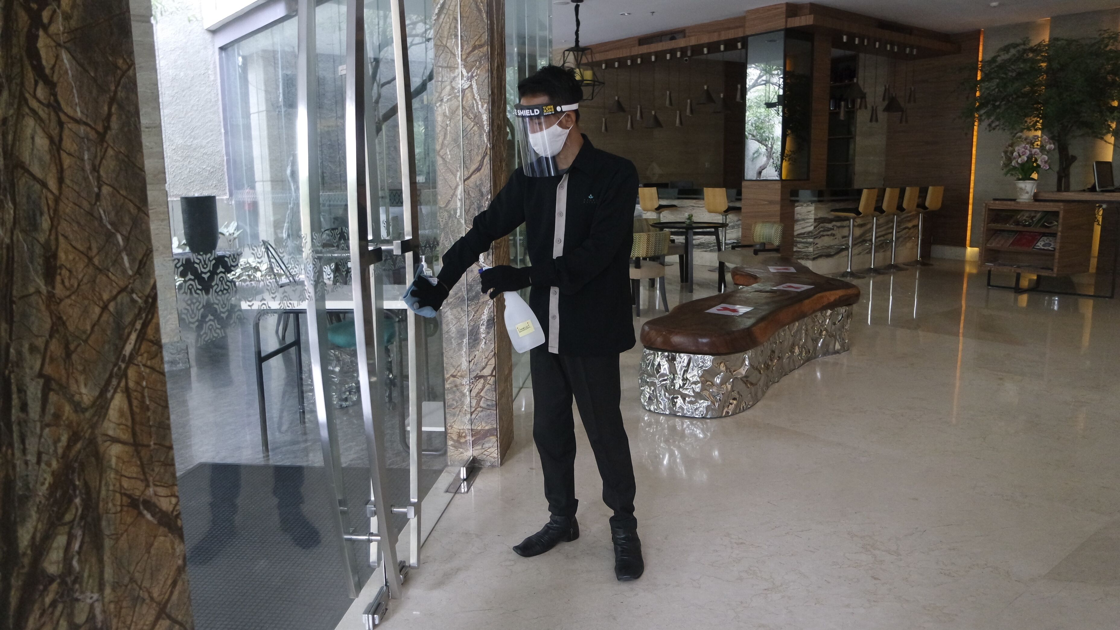 A hotel lobby with a reception desk, seating area, and a glass partition.