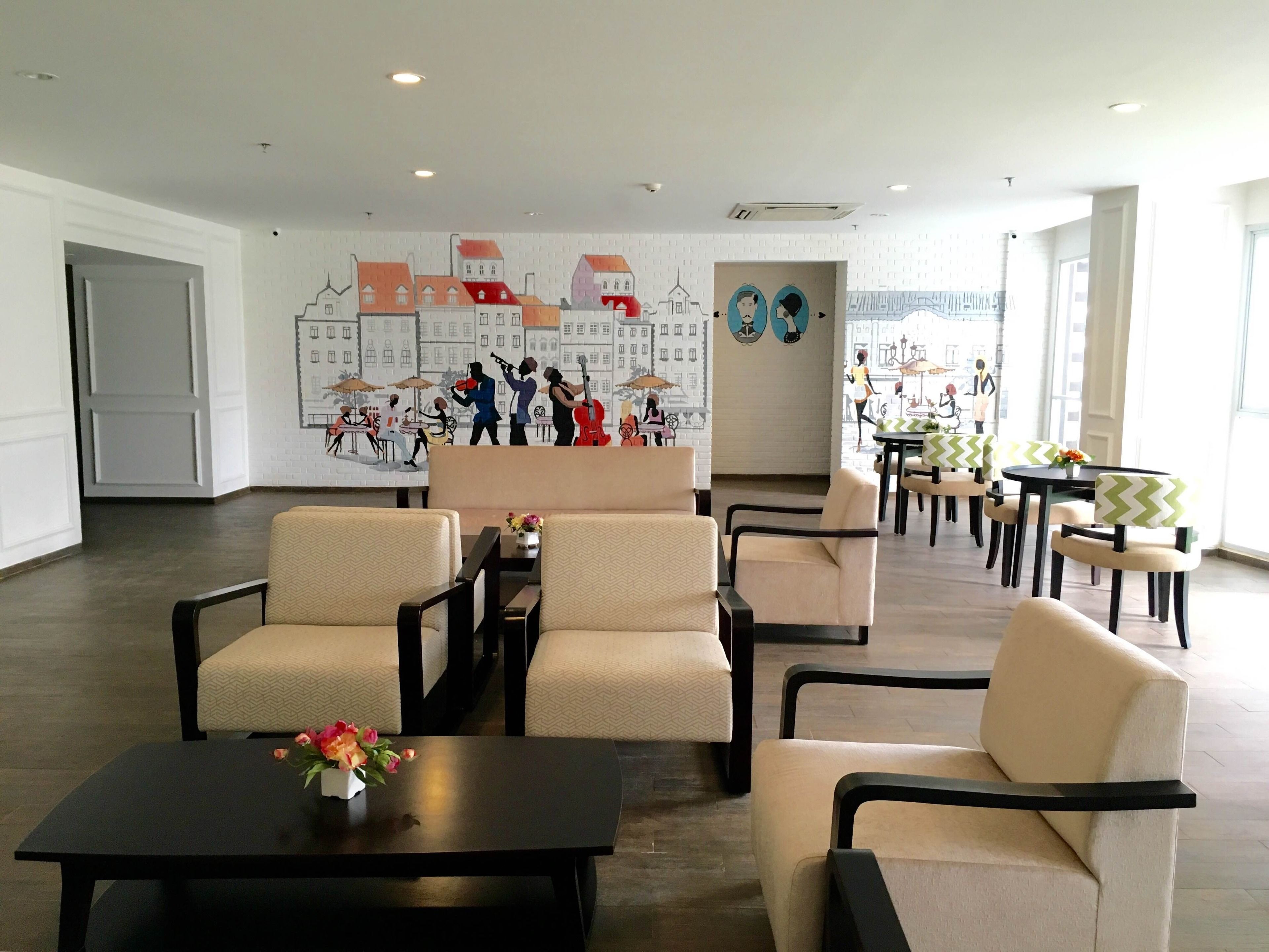 A spacious lobby with a mural of a cityscape, comfortable seating, and a coffee table with flowers.