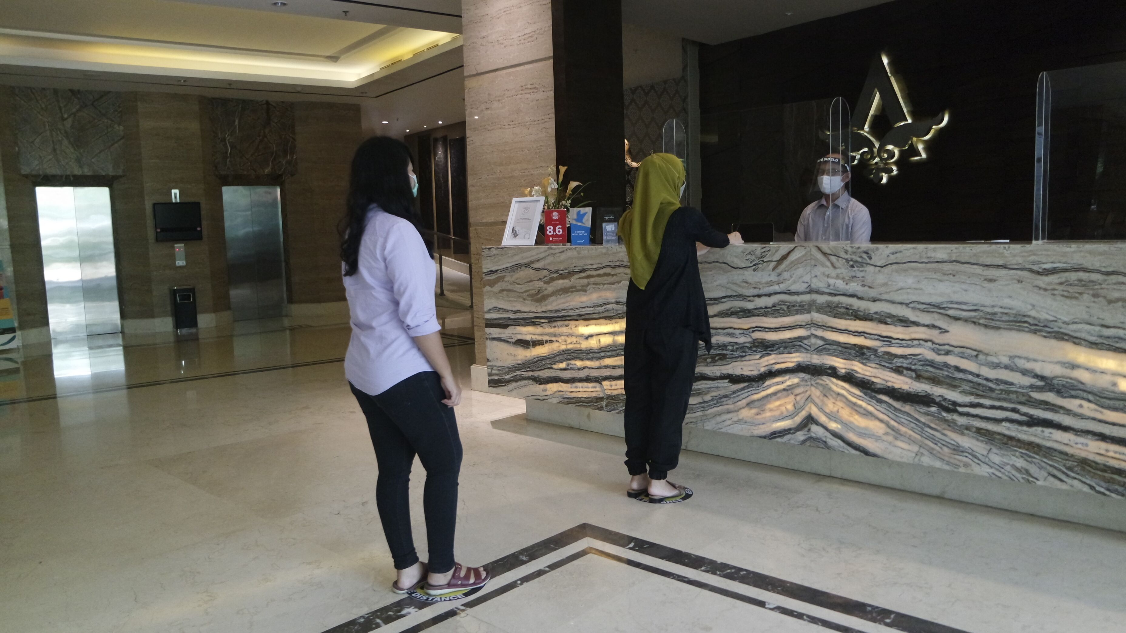 A reception area with a marble counter, a glass elevator, and a modern interior design.