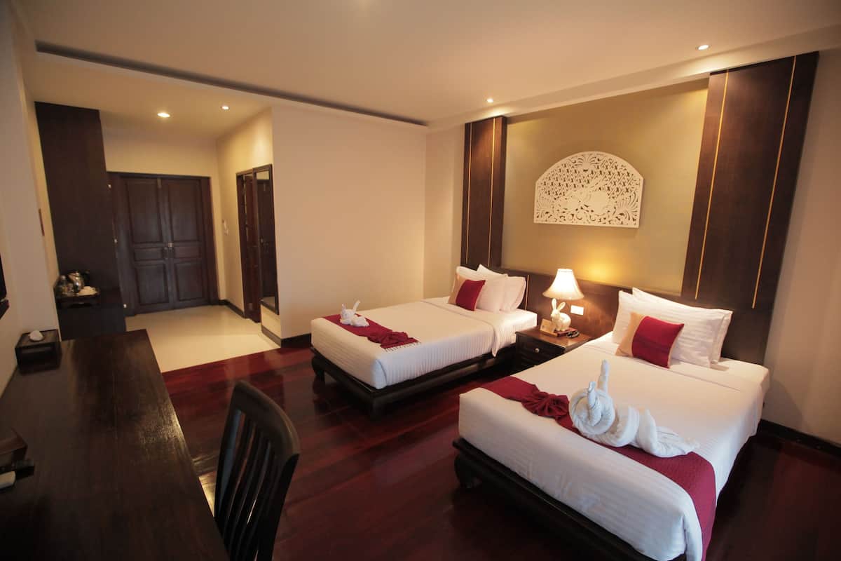 A hotel room with two beds, a dining table, and a small kitchen area.