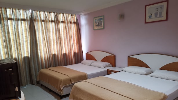 Camera d'albergo con due letti, una scrivania e una televisione.