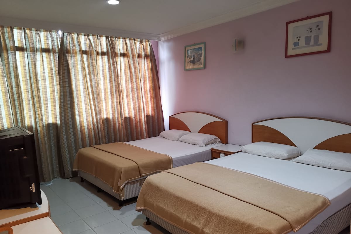 A hotel room with two beds, a desk, and a television.