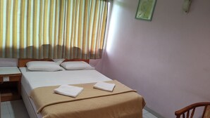 Una camera d'albergo ordinata con un letto, una scrivania e una sedia.